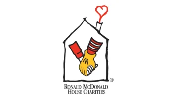A Simple Drawing Of A House With Two Hands Shaking Inside—one Yellow With A Red-and-white Striped Sleeve—and A Red Heart Above The Chimney. Below Is The Text: Ronald McDonald House Charities.